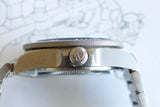 Side view of a titanium luxury dive watch with brushed case and engraved crown