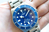 Close-up of a blue Tudor Pelagos Swiss luxury dive watch with stainless steel bracelet.