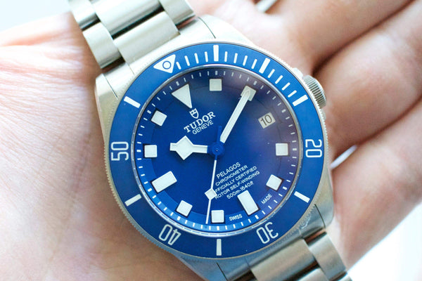 Close-up of a blue Tudor Pelagos Swiss luxury dive watch with stainless steel bracelet.