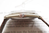 Side view of a vintage luxury watch with a brown leather strap and stainless steel crown