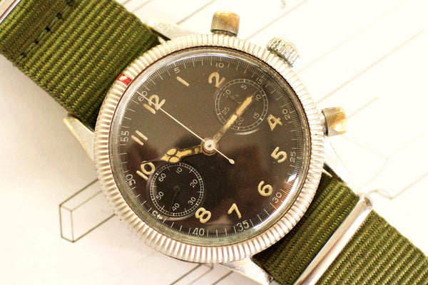 Vintage pilot watch with black dial, luminous numerals, and green fabric strap