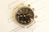 Vintage pilot's chronograph watch with black dial and luminous numerals on technical drawing