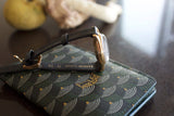 Elegant vintage gold wristwatch with black leather strap on patterned wallet, luxury style