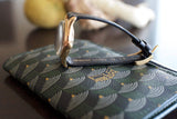 Vintage gold watch with black leather lizard strap on patterned wallet close-up