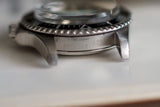 Close-up of stainless steel vintage dive watch case and bezel, focus on engraved serial number.
