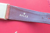 Close-up of a purple leather Rolex watch strap with silver buckle on a red background