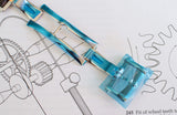 Close-up of a luxury watch clasp with protective blue film on a technical diagram background
