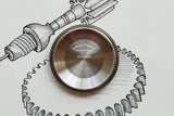 Close-up of a stainless steel Tudor watch case back on a hand-drawn sketch background.