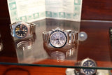 Three luxury Swiss-made wristwatches displayed on a reflective glass surface.