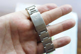 Close-up of a stainless steel luxury watch bracelet clasp held in a person's hand.