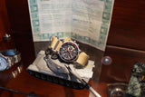 Luxury Swiss watch with a tan strap resting on a detailed model tank.